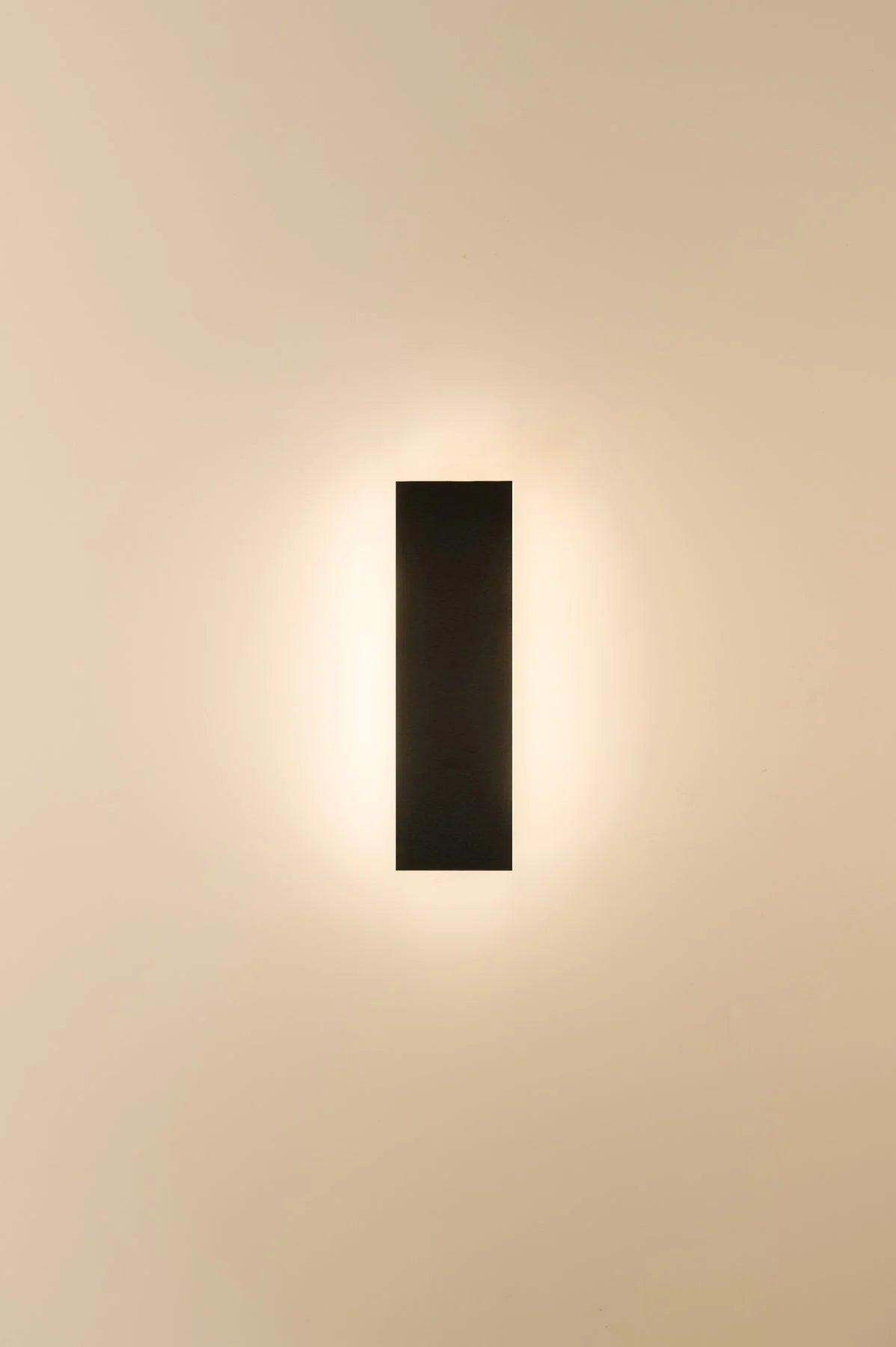 Modern wall-mounted light fixture on a beige wall
