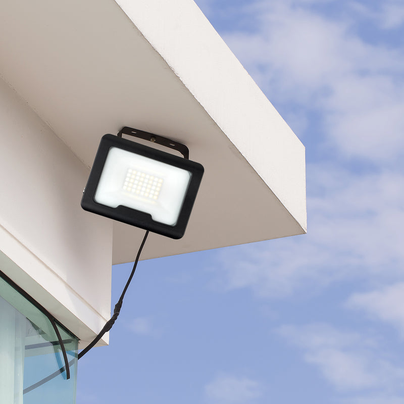 Outdoor flood light attached to a building exterior with a clear blue sky background