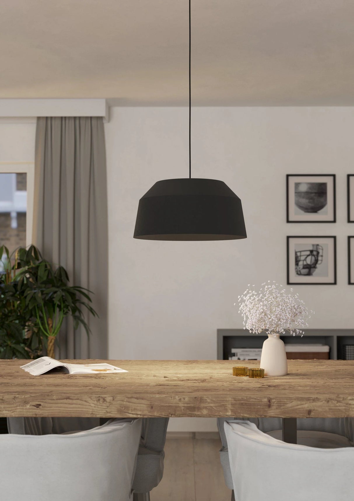 Modern dining room with a wooden table, black pendant light, and framed pictures on the wall.
