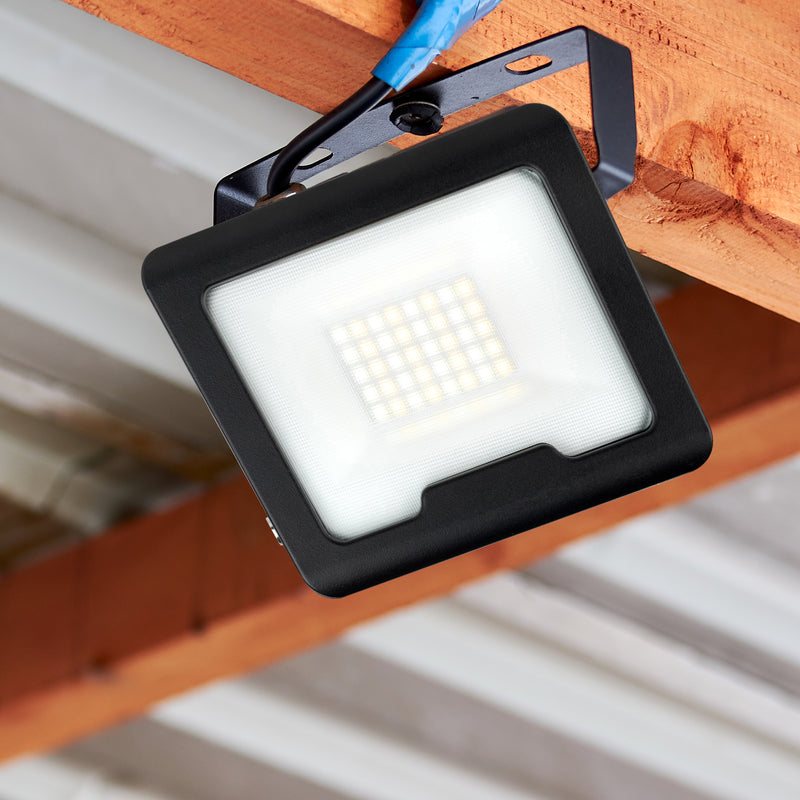 Black LED flood light attached to a wooden surface