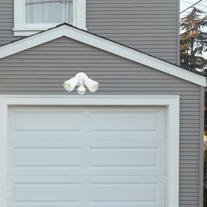 White outdoor security light fixture on a gray garage door