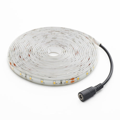 Roll of LED strip light with power connector on a white background
