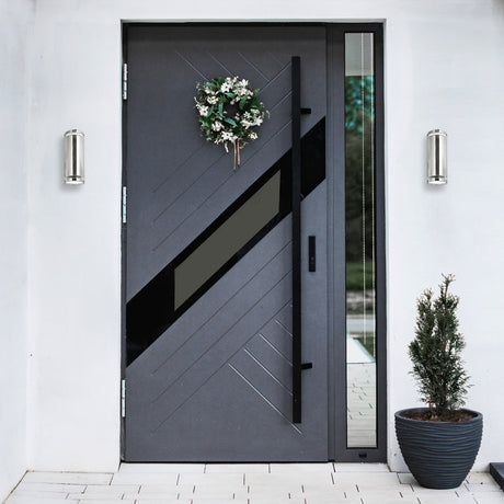 Modern gray front door with decorative wreath and plant on a white wall.