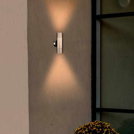 Modern wall-mounted outdoor light fixture on a concrete wall with a soft glow.