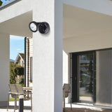 Black outdoor security camera mounted on a house exterior wall.