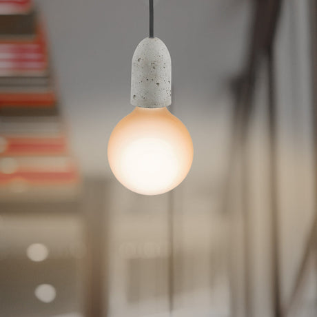 Light bulb with concrete base hanging against a blurred background