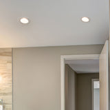 Two recessed lights on a ceiling in a room with neutral walls and a mirror.